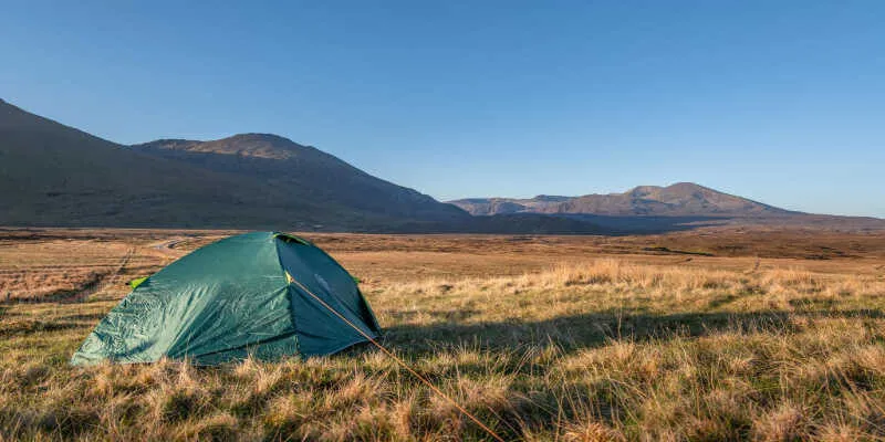 Small colorful tents pitched near a calm blue loch